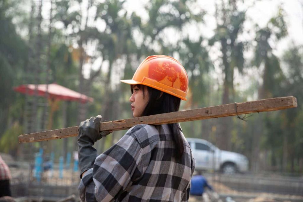 orang yang memegang kayu di proyek konstruksi
